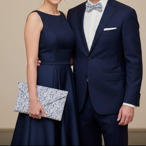 Pochette mariage en Liberty Eloïse bleu avec chaîne portée par une femme en robe bleu marine avec homme en costume bleu marine et noeud de papillon en liberty Eloïse bleu