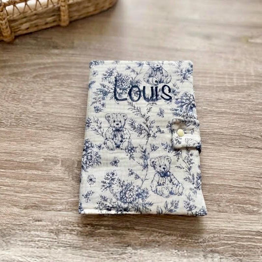 Protège carnet de santé bleu en gaze de coton motif toile de Jouy oursons et fleurs, personnalisé au prénom Louis en flocage bleu marine, fermeture par patte à bouton pression