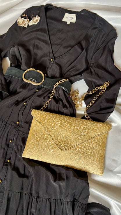 robe noire et sac pochette femme dorée