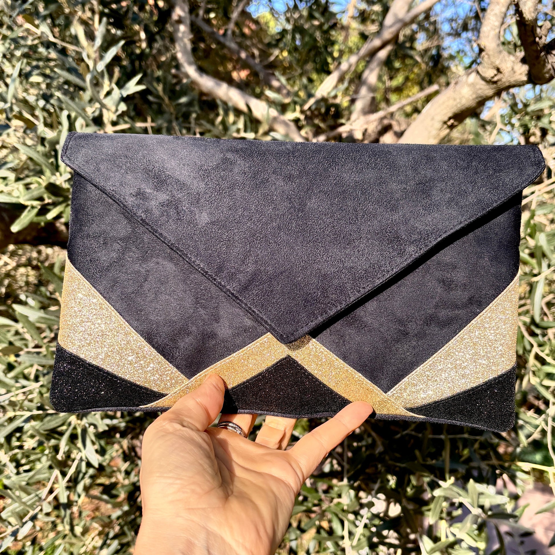 Pochette enveloppe noire suédine avec détails dorés graphiques