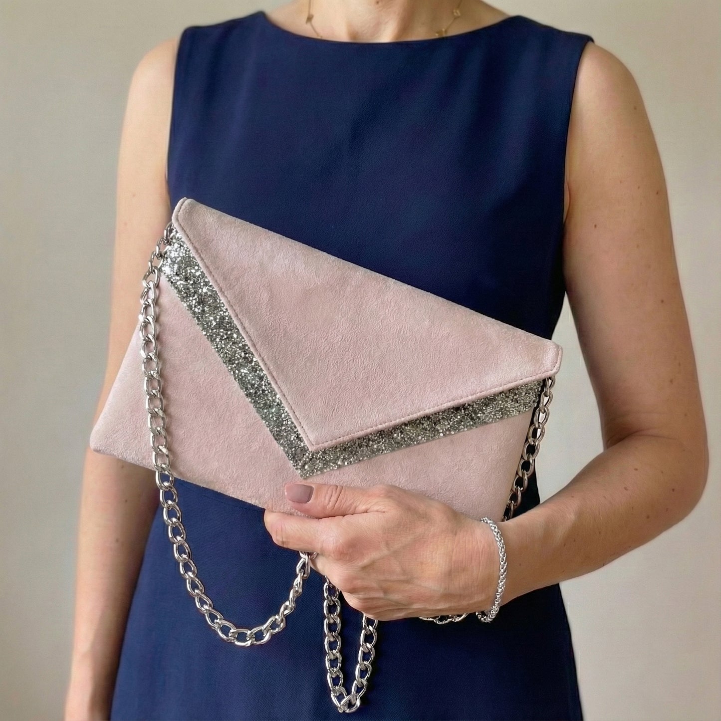 Pochette mariage rose poudré en suédine et paillettes argentée avec chaîne argentée portée avec une robe bleu marine