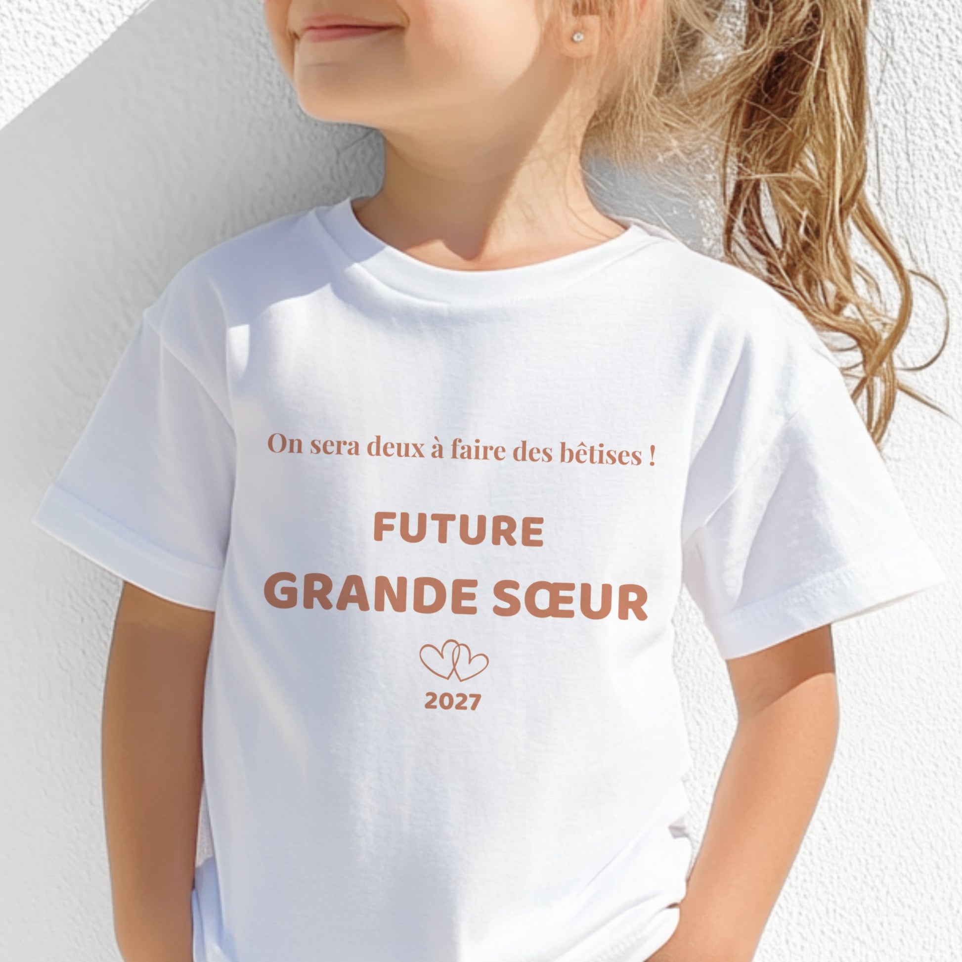 T-shirt enfant blanc future grande sœur, motif terracotta « on sera deux à faire des bêtises » avec deux cœurs entrelacés