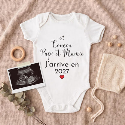 Body bébé Coucou Papi et Mamie J'arrive en 2027 posé pour une annonce de grossesse