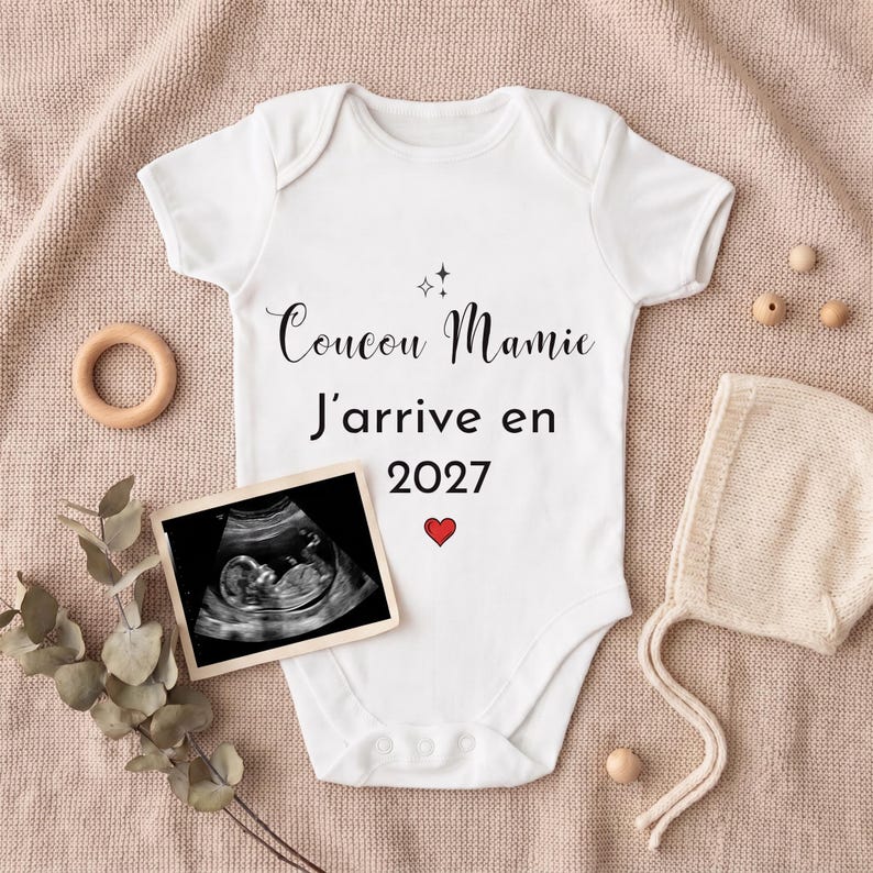 Body bébé Coucou Mamie J'arrive en 2027 posé pour une annonce de grossesse