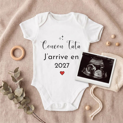 Body bébé Coucou Tata J'arrive en 2027 posé pour une annonce de grossesse