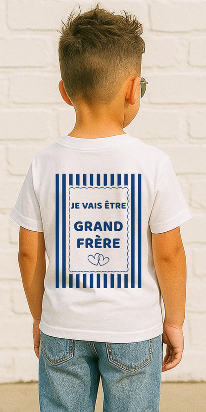 T-shirt enfant blanc futur grand frère, dos avec l'inscription Je vais être grand frère dans un cadre à rayures marinière bleu marine et deux cœurs entrelacés