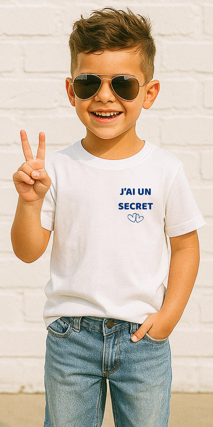 T-shirt enfant blanc futur grand frère, avant avec l'inscription J'ai un secret et deux cœurs entrelacés bleu marine