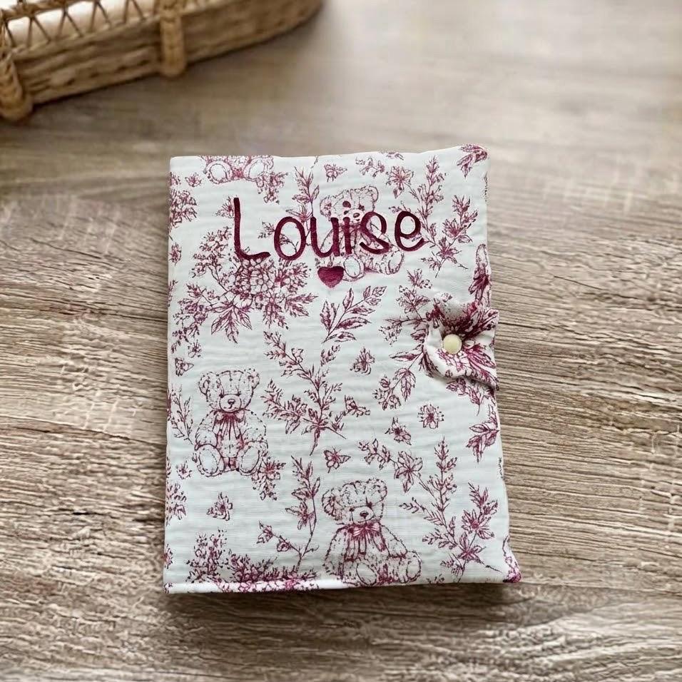 Protège carnet de santé bordeaux en gaze de coton motif toile de Jouy oursons, personnalisé au prénom Louise en flocage bordeaux avec un petit cœur sous le prénom