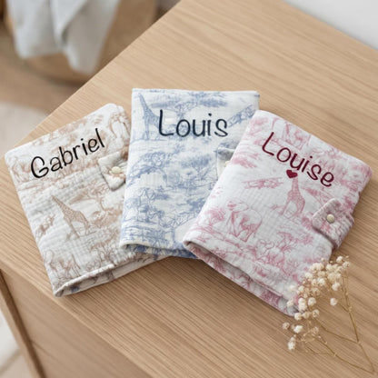 Trois protège carnets de santé en gaze de coton motif toile de Jouy Safari, coloris beige, bleu et rose, personnalisés aux prénoms Gabriel, Louis et Louise, avec un cœur sous Louise