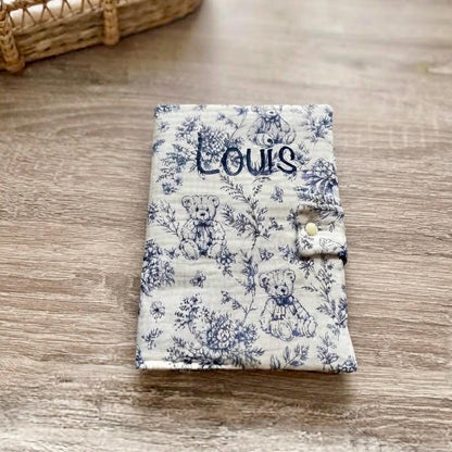 Protège carnet de santé bleu en gaze de coton motif toile de Jouy oursons et fleurs, personnalisé au prénom Louis en flocage bleu marine, fermeture par patte à bouton pression