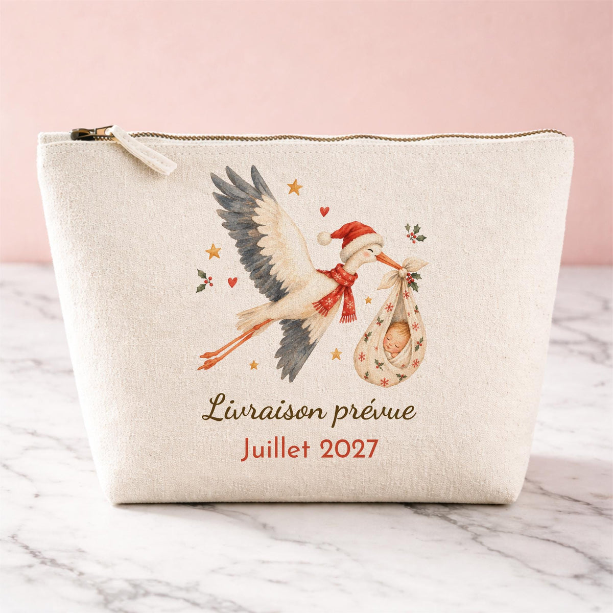 Trousse en coton naturel personnalisée pour annonce de grossesse à Noël : cigogne aquarelle en bonnet de Noël portant bébé dans un baluchon, texte Livraison prévue Juillet 2027