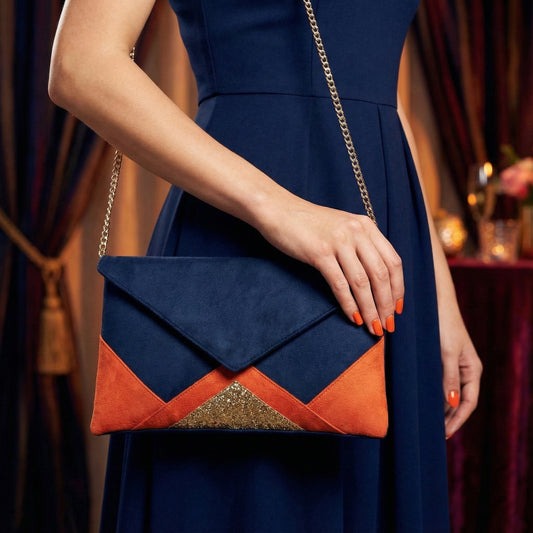 Pochette femme  format enveloppe bleu marine et orange en suédine avec chaîne dorée portée avec une robe bleu marine