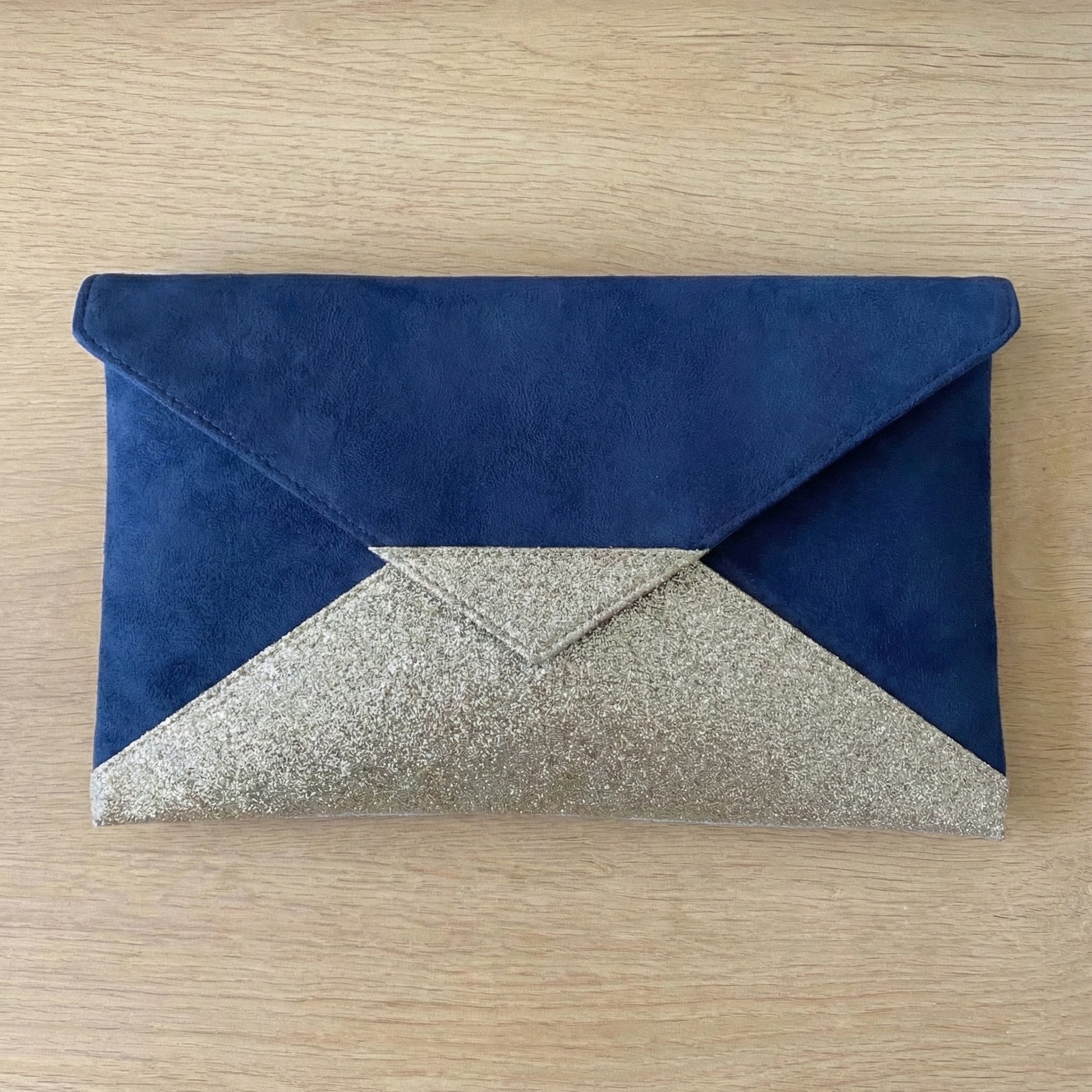 Vue à plat du sac de soirée bleu marine et doré montrant le contraste des matières